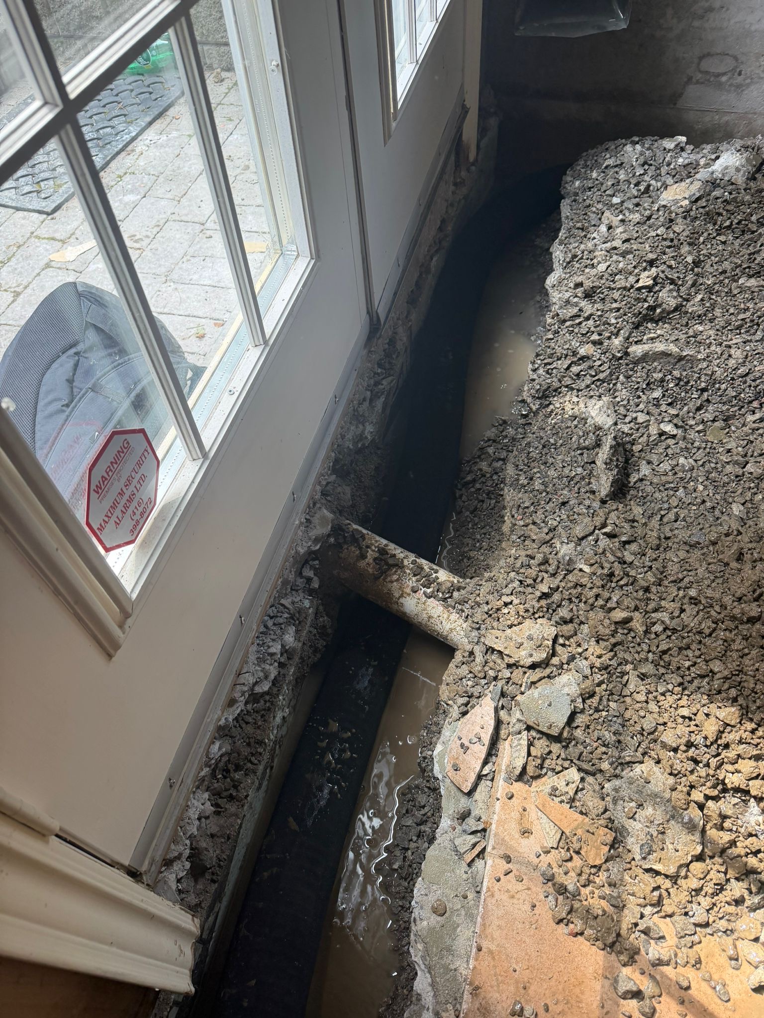 Basement drainage pipe connecting to the main weeping tile system near an exterior door in Pickering.