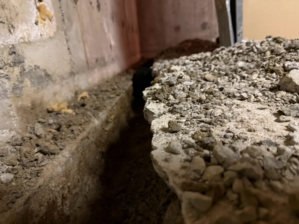 Excavated basement trench prepared for new weeping tile installation in an Aurora home.