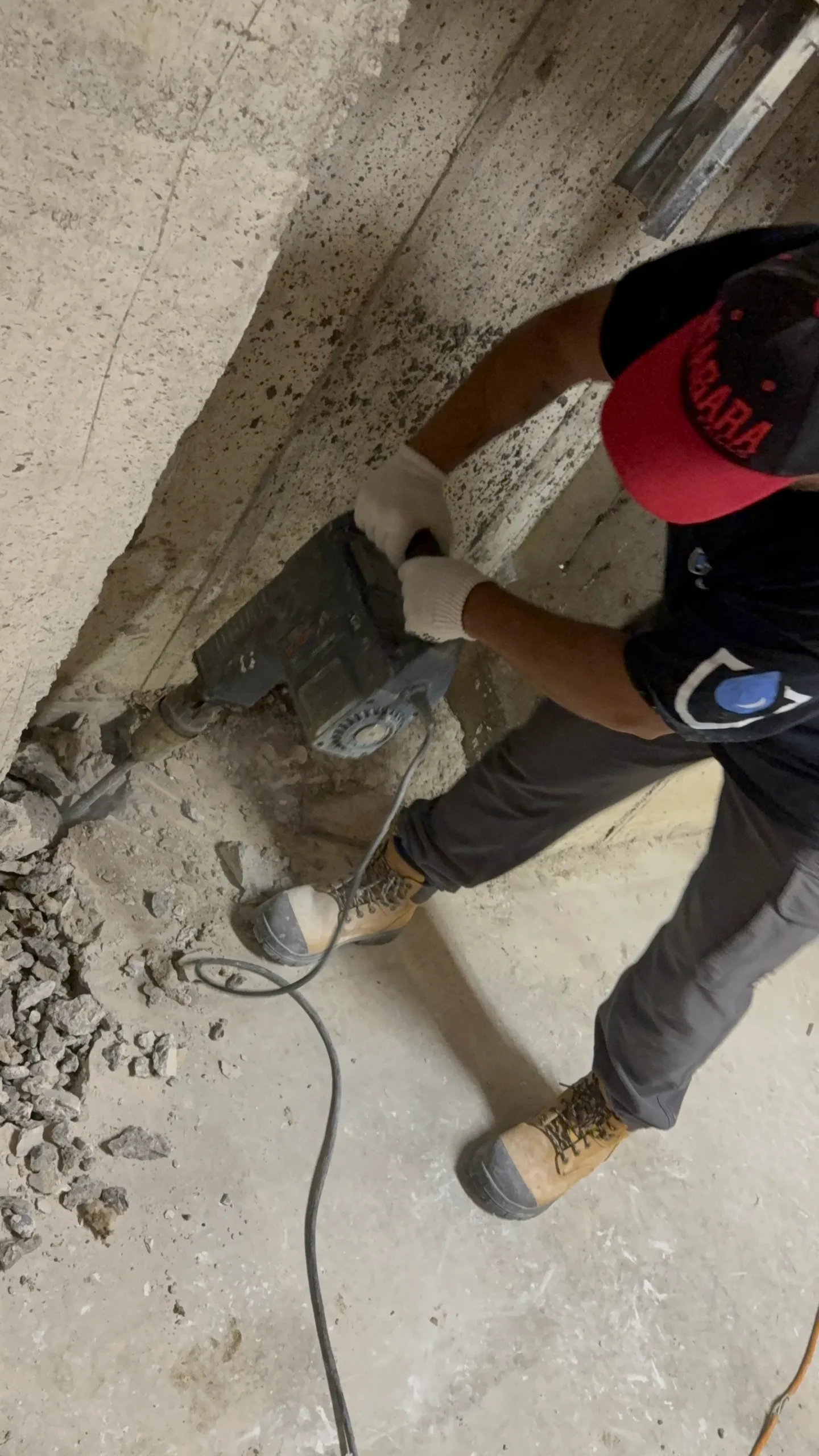 Contractor using a jackhammer for concrete floor demolition during interior waterproofing in Aurora.