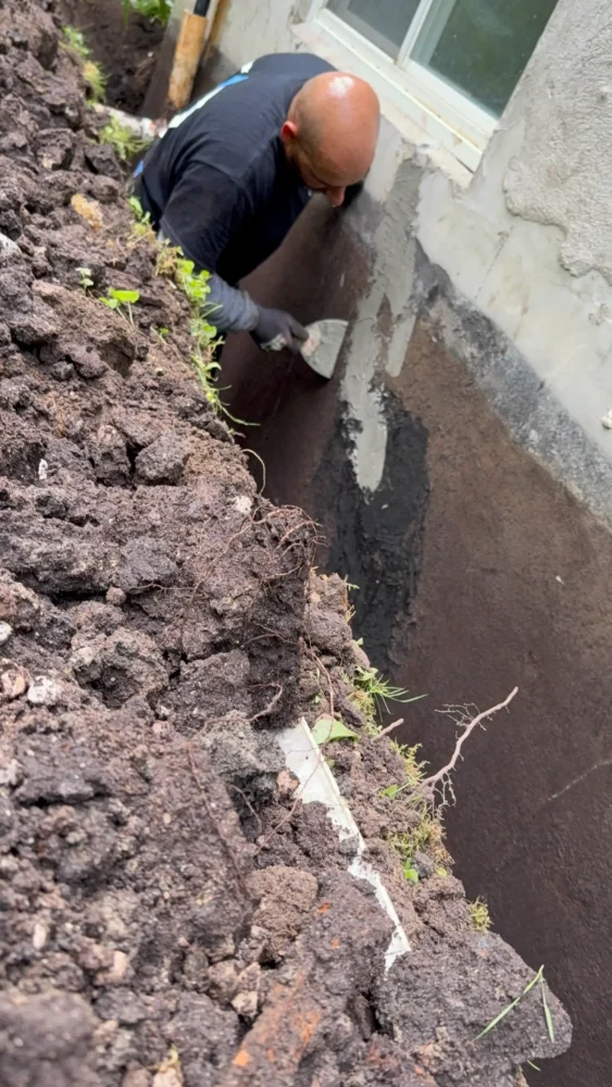 Waterproofing contractor using a trowel to apply hydraulic bonding concrete to seal foundation wall cracks in Innisfil.