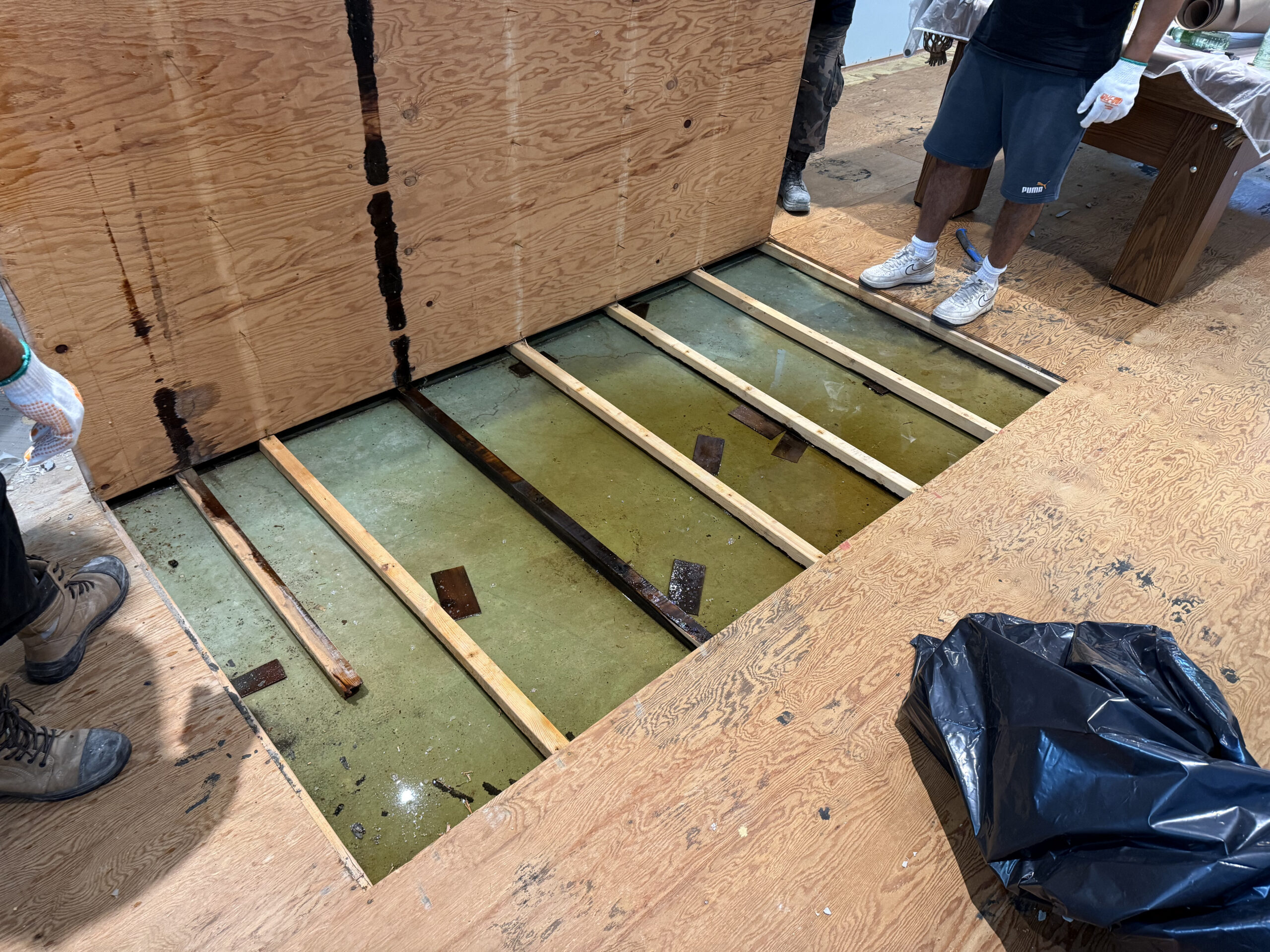 Exposed wooden subfloor revealing severe basement water pooling in North York, highlighting the need for a professional interior drainage system.