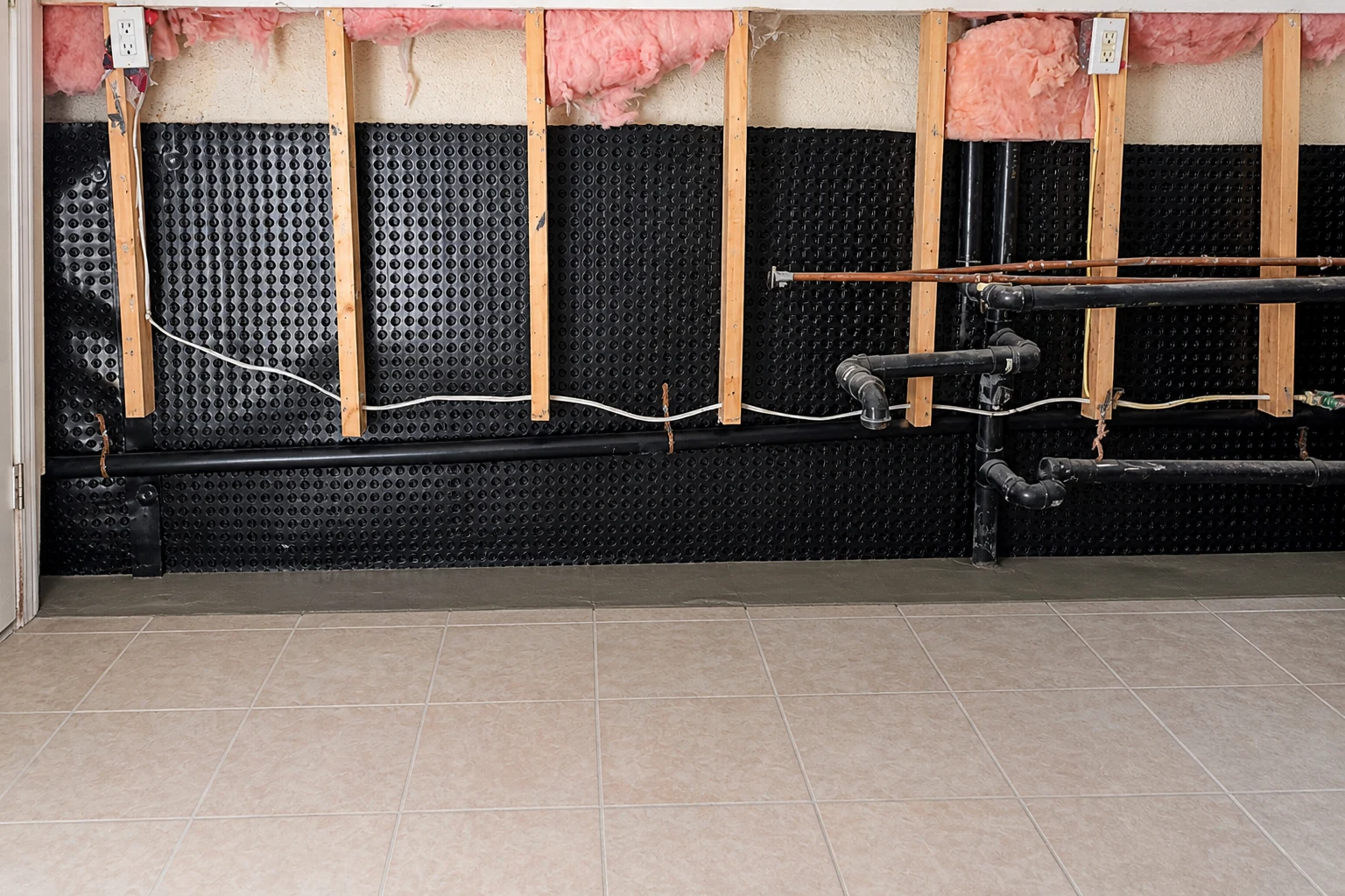 Black dimple membrane and repaired perimeter floor in a basement waterproofing installation